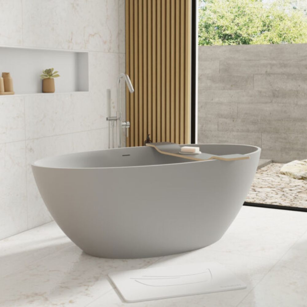 A modern freestanding oval bathtub in a minimalist bathroom setting with a wooden slat partition and a large window looking out to greenery.