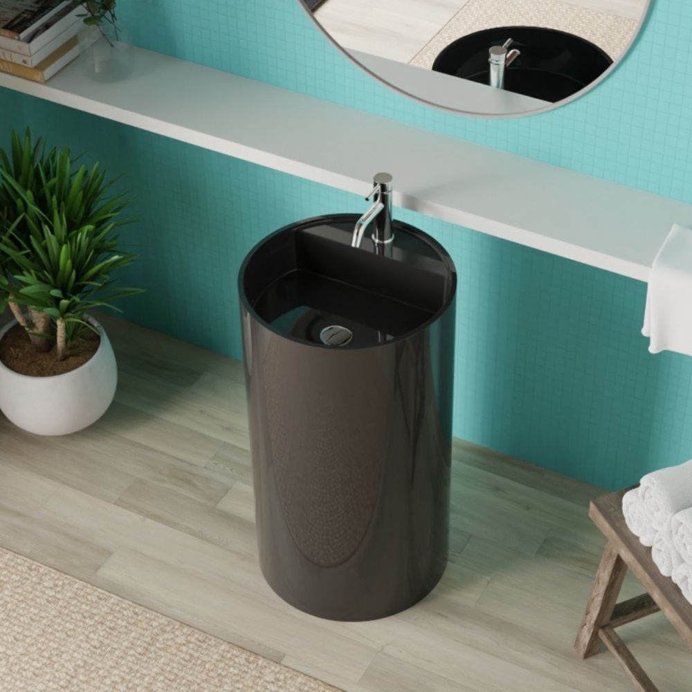 A dark brown glossy cylindrical pedestal sink with a chrome faucet, set in a modern bathroom with a turquoise wall, white floating shelf, and a potted plant.