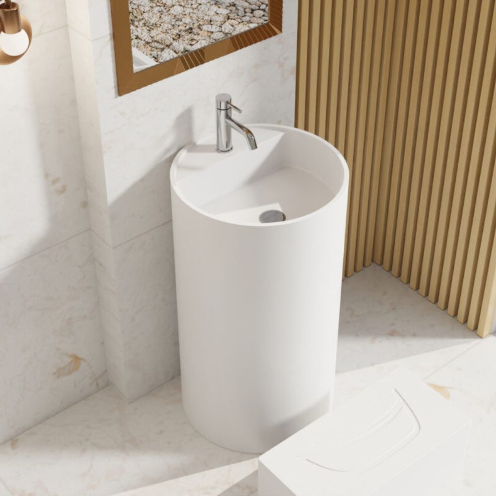 A modern white ceramic pedestal sink with a chrome faucet, set in a bathroom with marble tiles, a slatted wood screen, and a mirror.