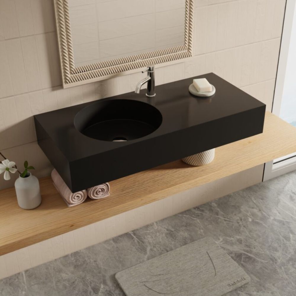 Modern bathroom setup with a black sink on a wooden vanity, mirror, and bath mat.