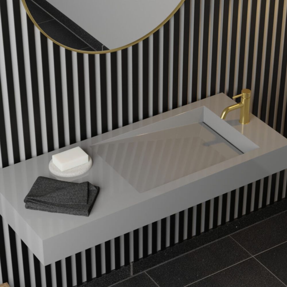 Bathroom sink with gold faucet, black and white striped wall, and gray countertop.