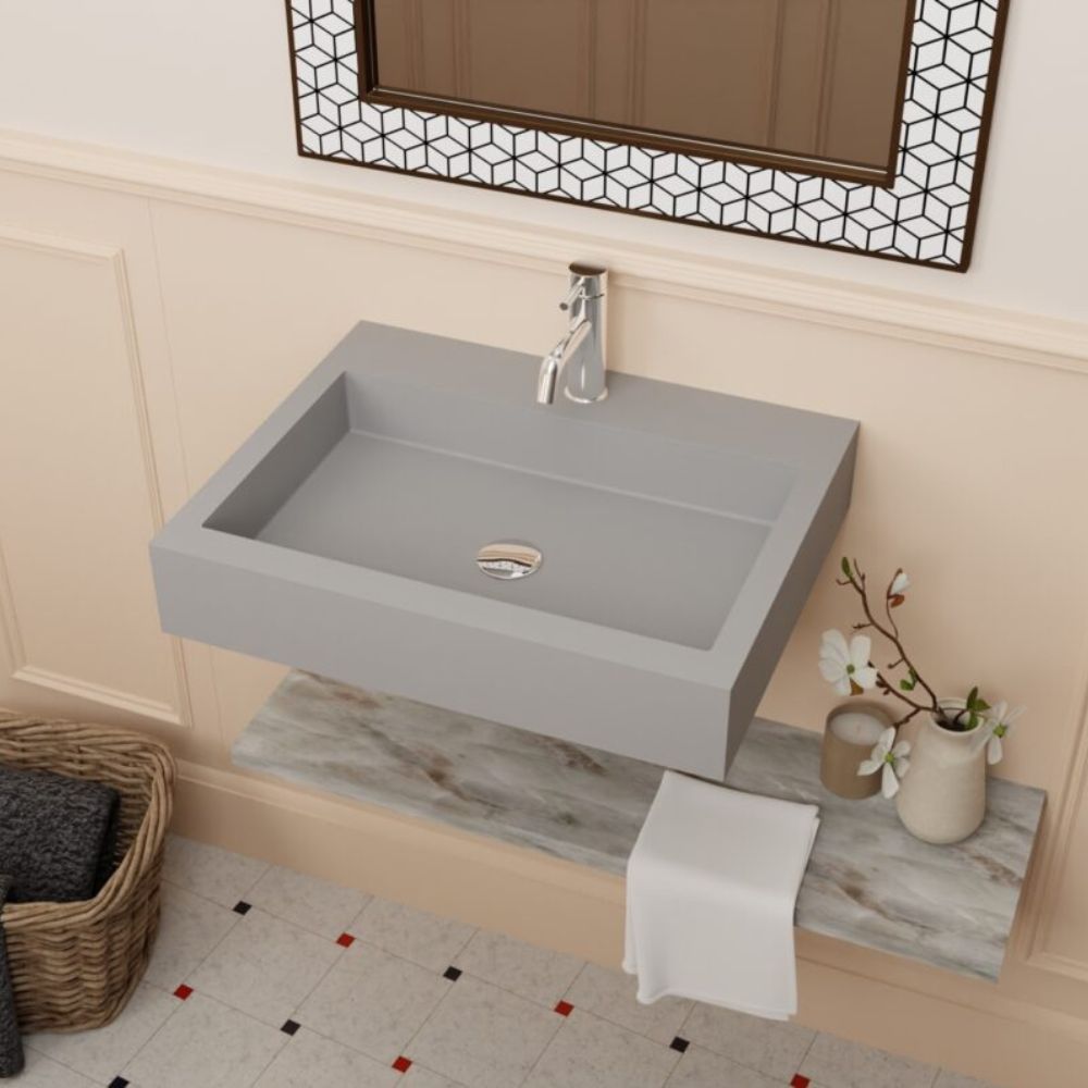 Gray wall-mounted sink in a bathroom setting with a mirror and decorative elements.