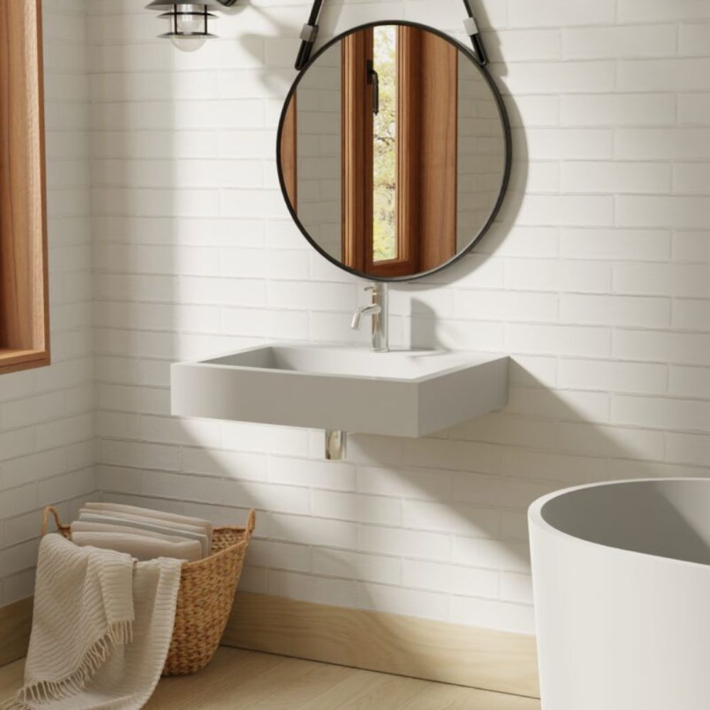 Bathroom with a wall-mounted sink and round mirror on a tiled wall.