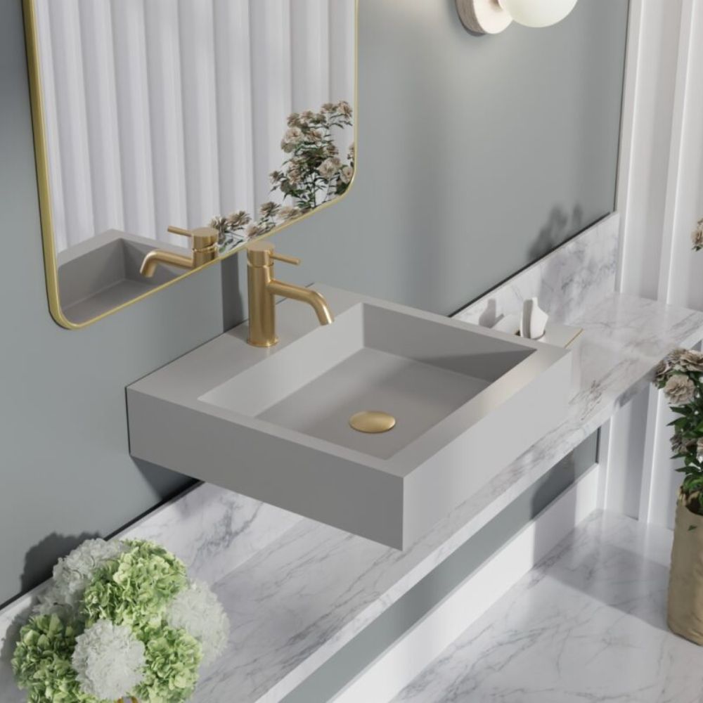 Bathroom vanity with gray sink and gold faucet, featuring a mirror and decorative elements.