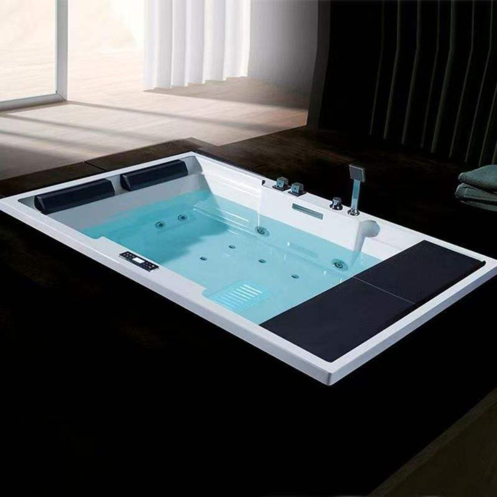Modern rectangular hot tub with blue water in a room with large windows.